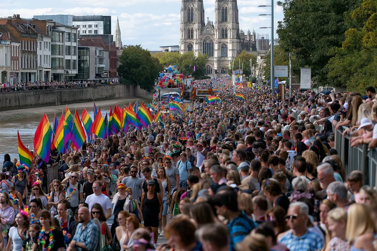 Des drapeaux arc-en-ciel et des chars décorés défilent dans une rue riveraine bondée.