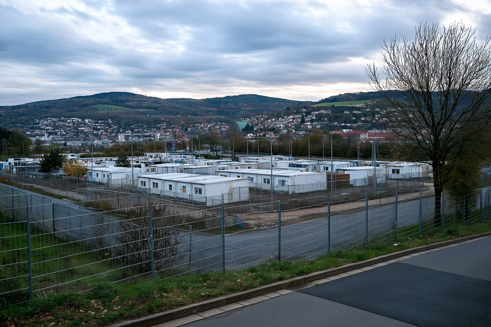 Un complexe résidentiel clôturé, composé de bâtiments en conteneurs, situé à la périphérie d'une ville allemande.
