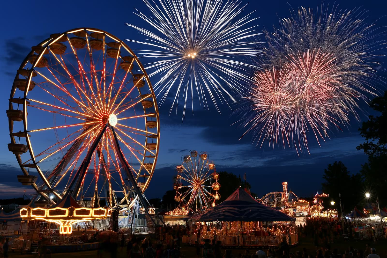 Une fête foraine illuminée avec une grande roue et des manèges au crépuscule sur le Heiligengeistfeld à Hambourg