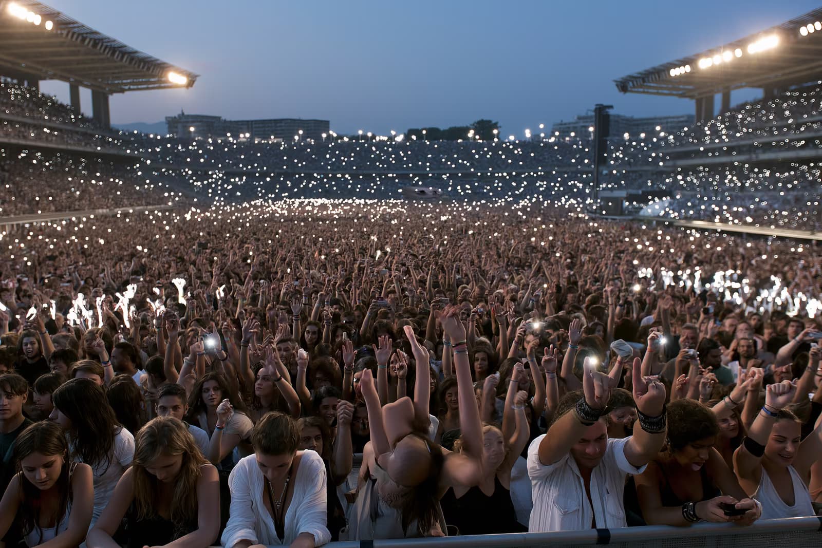 Une foule nombreuse dans un stade illuminée par la lumière du soir lors d'un concert d'été à Munich.