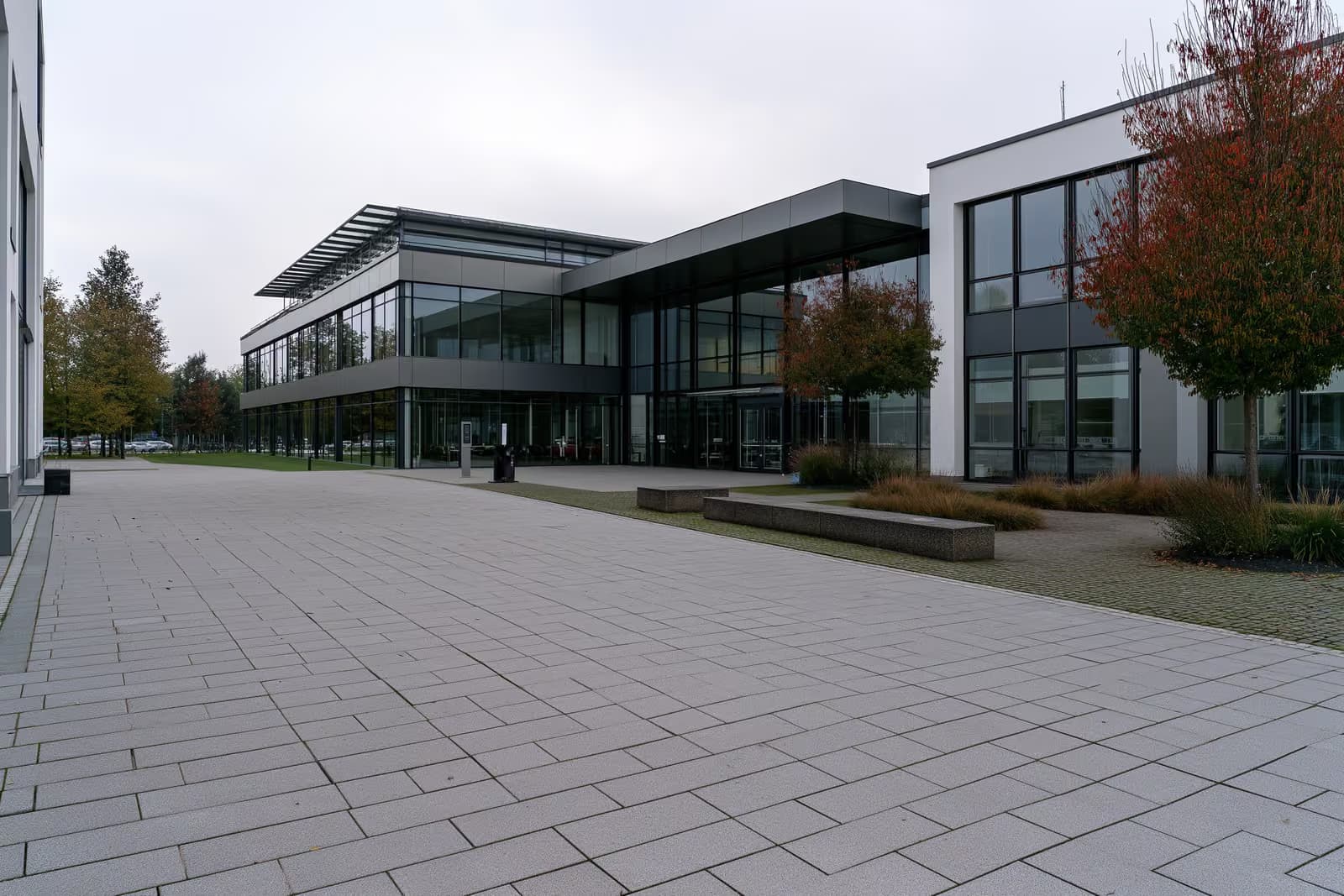 Un bâtiment moderne d'agence pour l'emploi allemande avec une vaste cour pavée vide sous un ciel couvert.