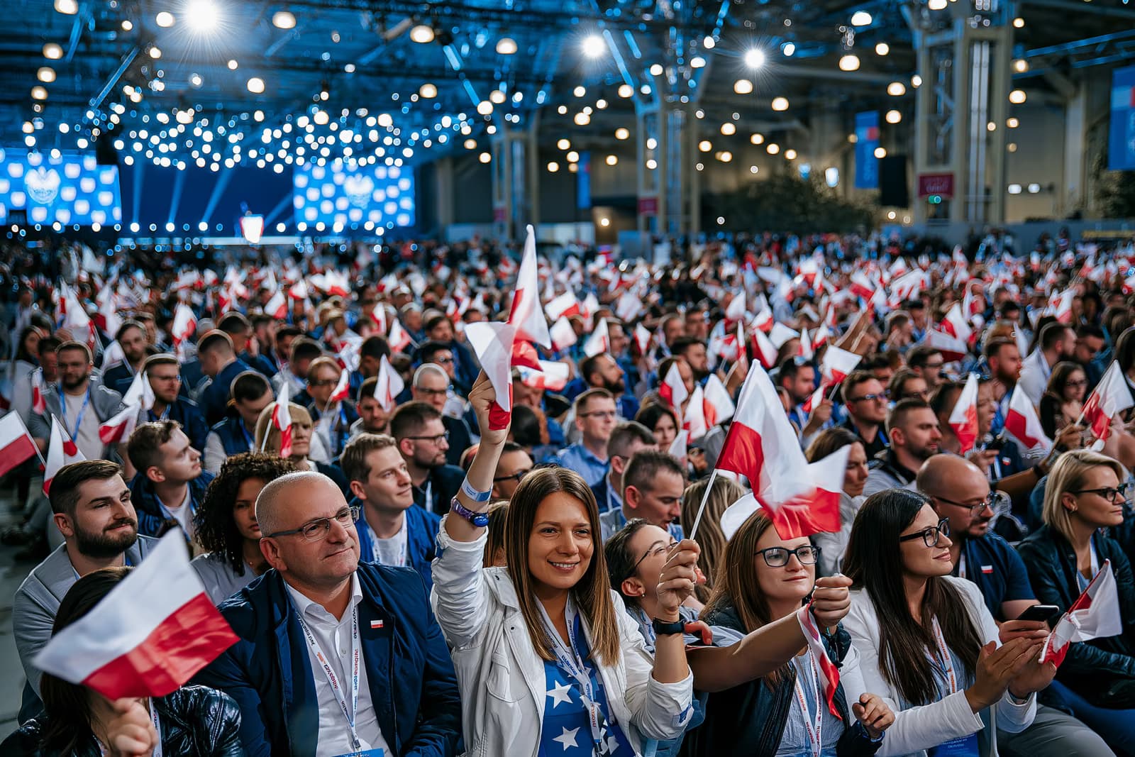 Une foule compacte dans le hall d'exposition agite de petits drapeaux sous un éclairage événementiel cru lors du lancement de la campagne de l'AfD à Magdebourg, avec une scène au loin.