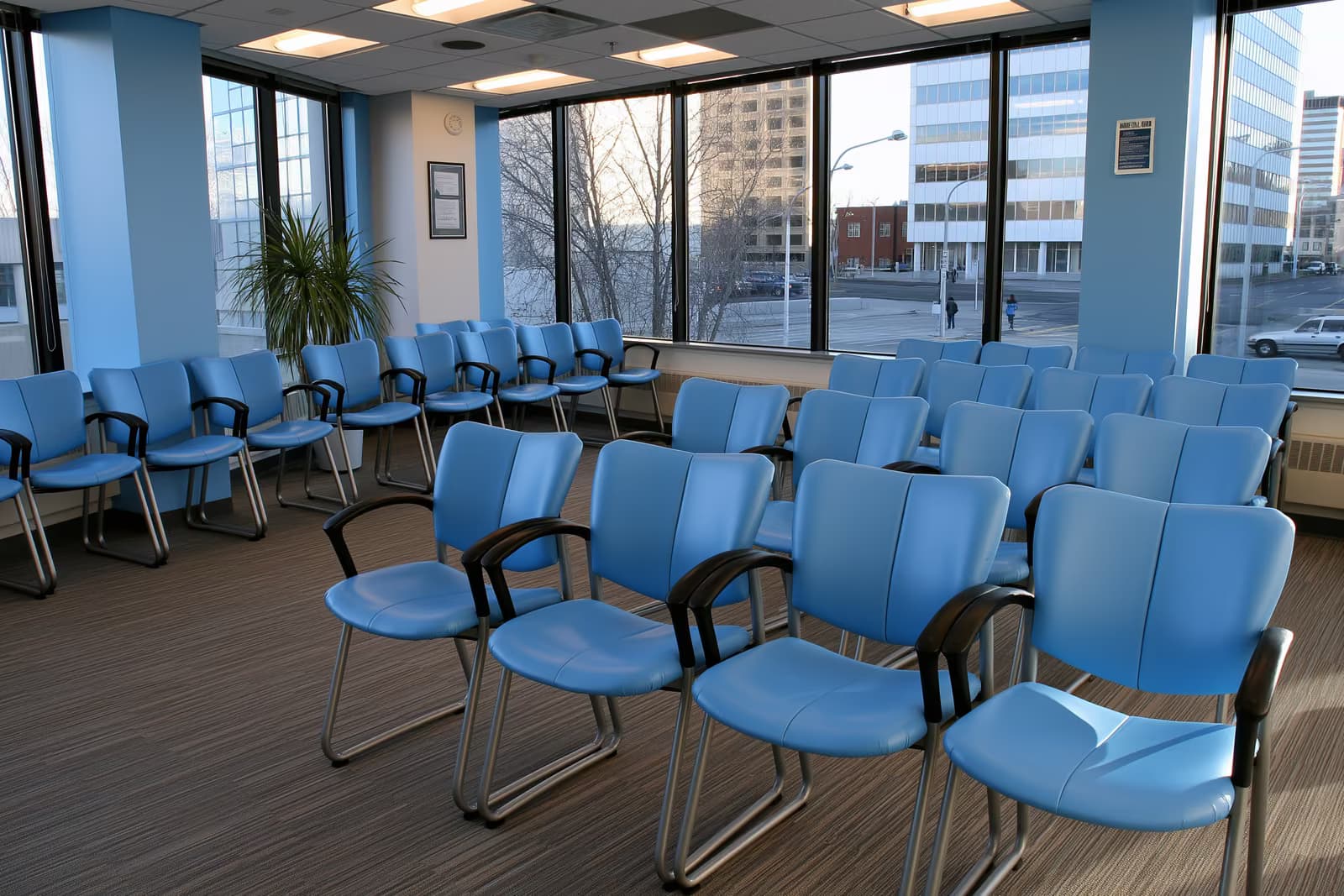 Une salle d'attente calme dans un bureau public, avec des rangées de chaises vides et un comptoir d'accueil.